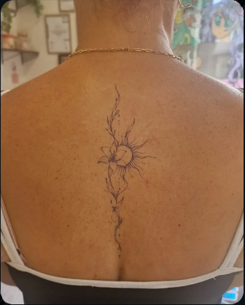Delicate fine line flower tattoo with flowing botanical details on the upper back